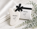 SilkyBare gua sha tool with packaging on white silk pillowcase and gift box