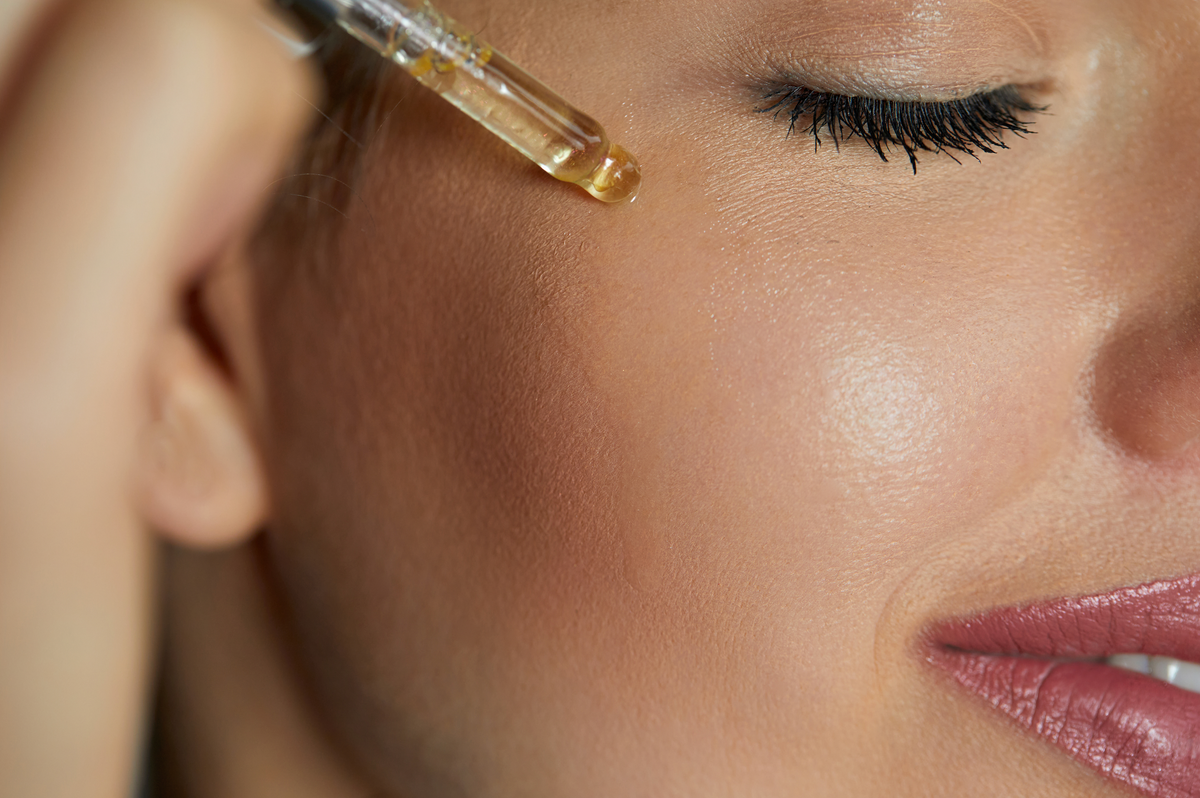 woman using face oil with natural ingredients on her face