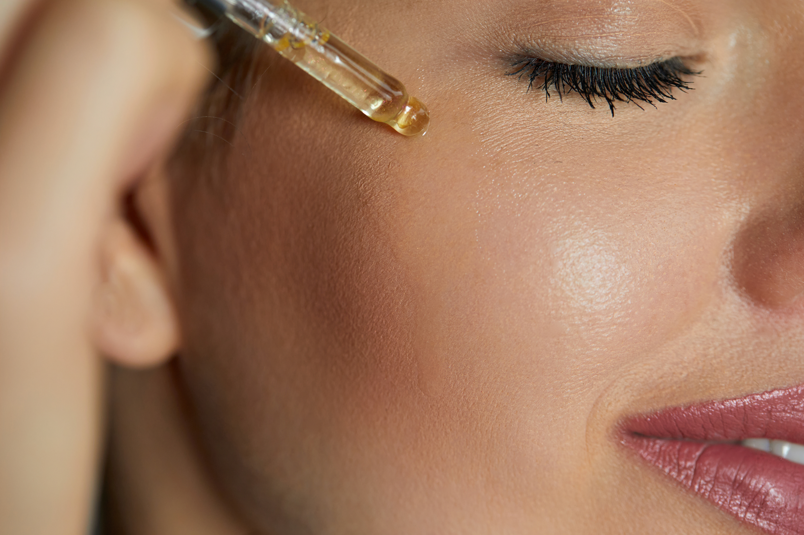woman using face oil with natural ingredients on her face