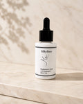 SilkyBare Hyaluronic Acid Serum 30ml dropper bottle on a white marble surface — lightweight gel serum with four forms of hyaluronic acid, made in Australia