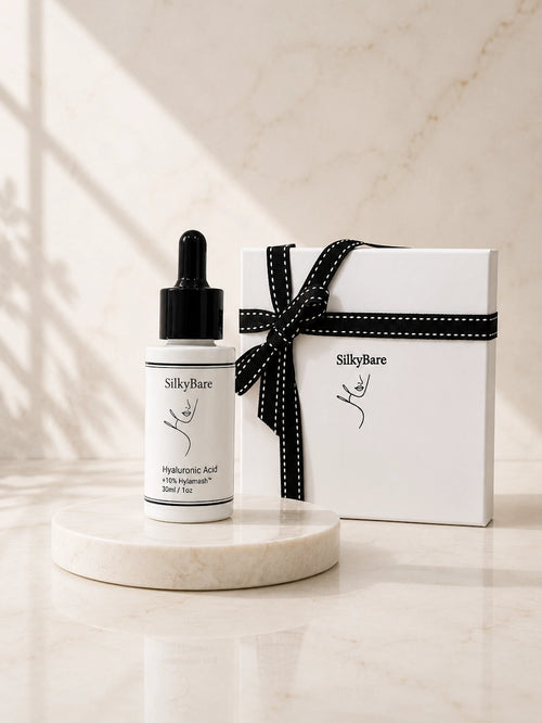 SilkyBare Hyaluronic Acid Serum 30ml dropper bottle beside a white SilkyBare gift box with black ribbon — perfect skincare gift for her